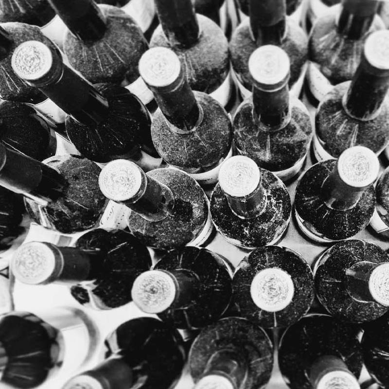 Black and white aerial photo of dusty wine bottles in rows