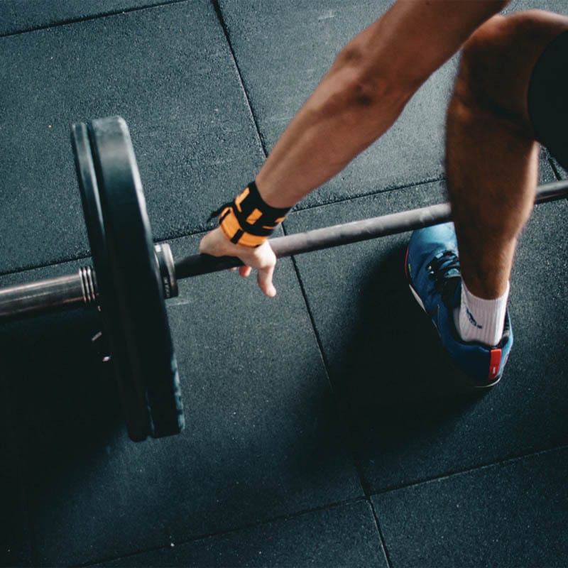 Closeup of a person inside a workout facility about to lift a bar with plates